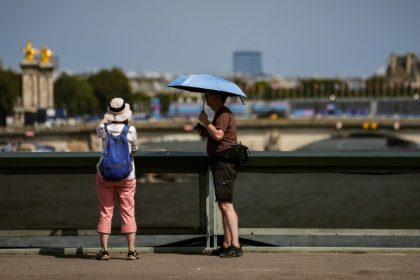 Un homme se protège du soleil avec un parapluie le 30 juillet 2024 à Paris