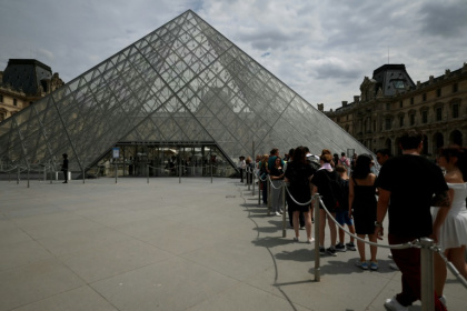 Des visiteurs font la queue devant la pyramide de l'architecteIeoh Ming Pei au musée du Louvre à Paris, le 11 juillet 2024