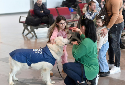 Des enfants s'approchent de Dino, un golden retriever conduit par sa dresseuse Vesna Kiskovska (d) à l'aéroport international de Skopje, le 29 janvier 2025 en Macédoine du Nord