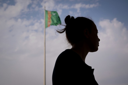 Une jeune feme devant un drapeau du Turkménistan, le 28 juin 2023 à Achkhabad