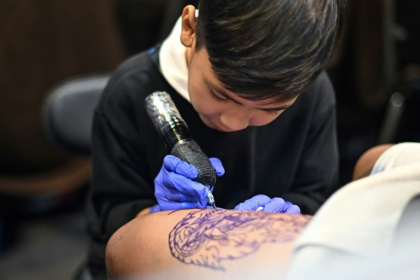 Napat Mitmakorn, 9 ans, travaille sur le tatouage de son oncle lors de la 2025 Thailand Tattoo Expo à Bangkok, le 15 mars 2025 en Thaïlande