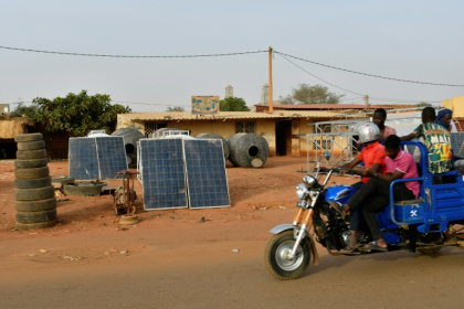 Une moto-taxi passe devant des panneaux solaires en vente dans une rue de Niamey, le 3 avril 2025