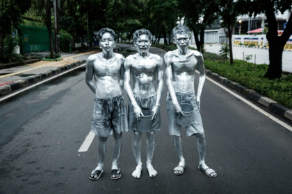 Les artistes de rue Keris Munandar (d), son frère Ari Munandar (c) et leur voisin Riyan Ahmad Fazriyansah dans une rue de Jakarta, le 1er avril 2025 en Indonésie - Yasuyoshi CHIBA (AFP)