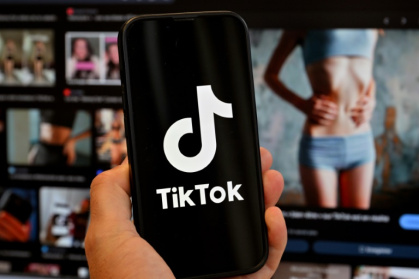 Photo d'illustration du 7 mai 2025 montrant le logo de Tik Tok sur un smartphone devant un écran affichant l'image d'une femme très mince, alors que la tendance "skinnytok" promouvant la minceur inquiète les experts - Loic VENANCE (AFP) Photo d'illustration du 7 mai 2025 montrant le logo de Tik Tok sur un smartphone devant un écran affichant l'image d'une femme très mince, alors que la tendance "skinnytok" promouvant la minceur inquiète les experts - Loic VENANCE (AFP)