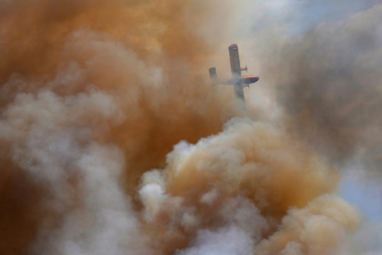 Un avion de lutte contre les incendies dans la fumée d'un feu de forêt près du village d'Abejera, dans la province de Zamora en Espagne, le 13 août 2025 - Nalini LEPETIT-CHELLA, Sabrina BLANCHARD, Jon WALTER (AFP)