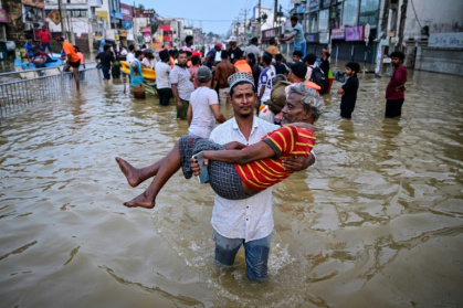 Un homme porte une personne âgée dans une rue inondée, le 30 novembre 2025 à Wellampitiya au Sri Lanka - Ishara S. KODIKARA (AFP)