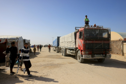 Des Palestiniens regardent des camions transportant de l'aide humanitaire arriver à Khan Younès, dans le sud de la bande de Gaza, après avoir franchi le poste-frontière de Rafah depuis l'Egypte, le 1er février 2026 - AFPTV STRINGER (AFP)