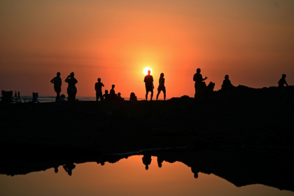 Des touristes profitent du soucher de soleil sur la plage d'El Tunco à La Libertad, au Salvador, le 13 février 2026 - Marvin RECINOS (AFP)