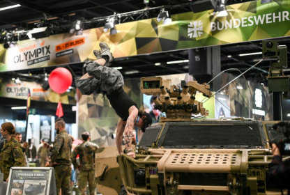 Un visiteur fait le poirier sur un véhicule de l'armée allemande, sur le stand de la Bundeswehr, au plus grand salon mondial du fitness, la Fibo, à Cologne (ouest de l'Allemagne), le 16 avril - Ina FASSBENDER (AFP)