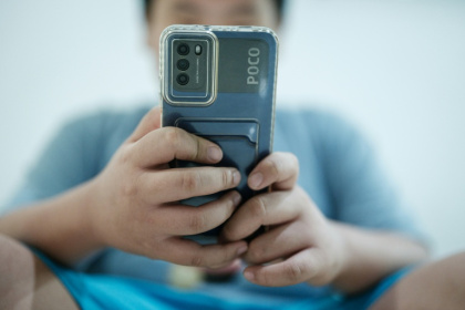 Un petit garçon regarde une vidéo sur son smartphone en attendant son père, à Jakarta, le 25 mars 2026 - YASUYOSHI CHIBA (AFP)