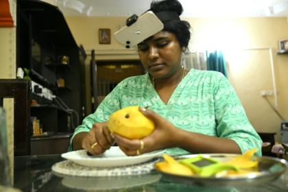 Nagireddy Sriramyachandra filme avec un téléphone ses gestes pendant qu'elle coupe une mangue pour entraîner un futur robot dopé à l'IA, le 15 mai 2026 à Madras, en Inde - R.Satish BABU (AFP)