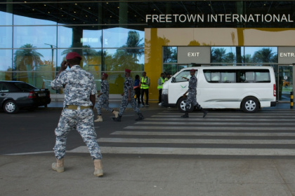 Des agents de sécurité escortent des migrants vers un centre de l'Agence nationale de santé publique (NPHA) après leur arrivée à l'aéroport international de Freetown, le 20 mai 2026 à Lungi, en Sierra Leone - - (AFP)