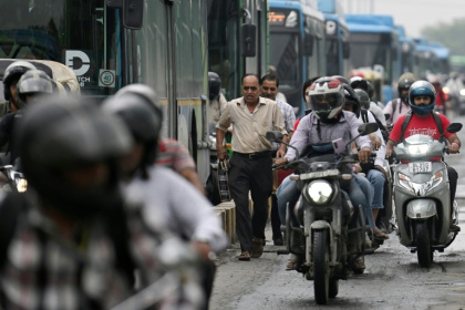 Des piétons au milieu de la circulation sur un pont à New Delhi, le 8 juillet 2026 en Inde - Arun SANKAR (AFP)