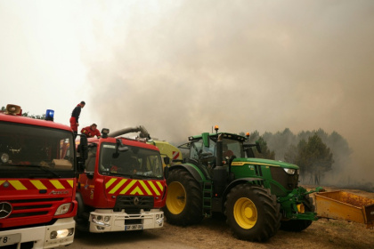 Des sapeurs-pompiers de la Brigade de sapeurs-pompiers de Paris ravitaillent leurs véhicules en eau à partir de la cuve du tracteur d'un agriculteur lors d'une intervention à Marcheprime, à l'ouest de Bordeaux, le 26 juillet 2026 - ALAIN JOCARD (AFP)