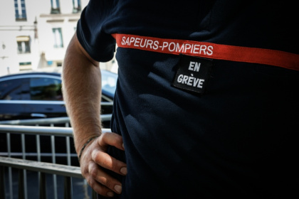 Un pompier avec "en grève" scratché sur la poitrine, devant  l'hôtel de Beauvau, à Paris, le 13 août 2026 - SIMON WOHLFAHRT (AFP)