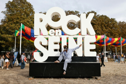 Un festivalier pose devant l'enseigne du festival Rock en Seine à Saint-Cloud dans les Hauts-de-Seine le 26 août 2026 - Simon WOHLFAHRT (AFP)