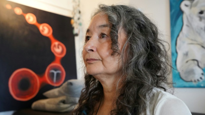 Naja Lyberth, psychologue et survivante de la campagne de stérilets imposés, pose devant un tableau représentant un utérus et un dispositif intra-utérin (DIU), à Nuuk, au Groenland, le 30 août 2024. - Mads Claus Rasmussen (AFP)