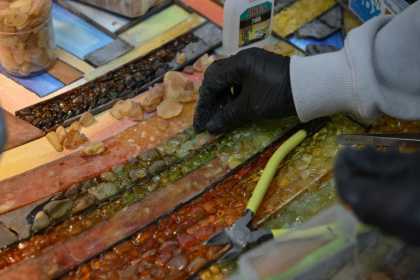 Une employée du groupe Amber Galbine travaillant l'ambre pour en faire des bijoux et des souvenirs à vendre, dans la région ukrainienne de Rivné, le 10 mai 2026 - Genya SAVILOV (AFP)