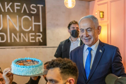 Le Premier ministre israélien Benjamin Netanyahu (d) échange avec des sympathisants venus lui offrir un gâteau pour son 77e anniversaire, lors d’une rencontre dans un café à Dimona, le 21 octobre 2026 en Israël - Ilia YEFIMOVICH (AFP)